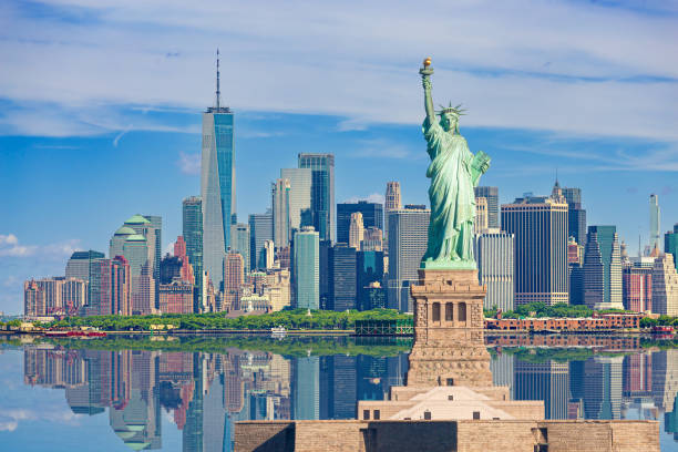 statue of liberty and new york city skyline with manhattan financial district, world trade center, empire state building and blue sky. - new york stockfoto's en -beelden