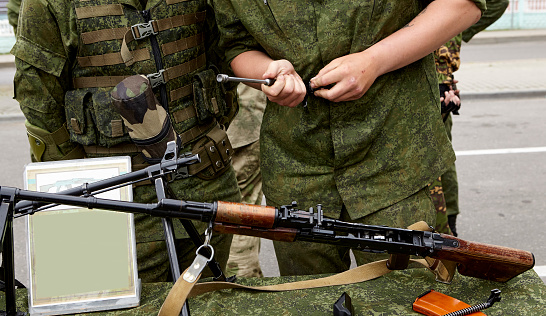 Light machine gun on the table. The soldiers are considering Russian-made weapons.