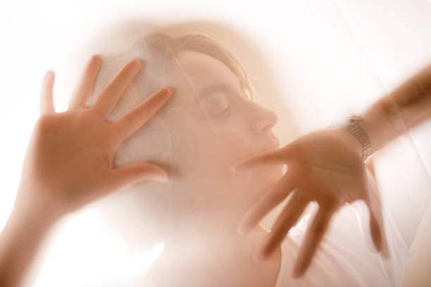 istock Woman pressing her hands against a sheer fabric while looking away 1454221809