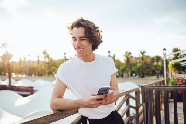 istock Happy young man in casual wear browsing smartphone on seafront 1454222994
