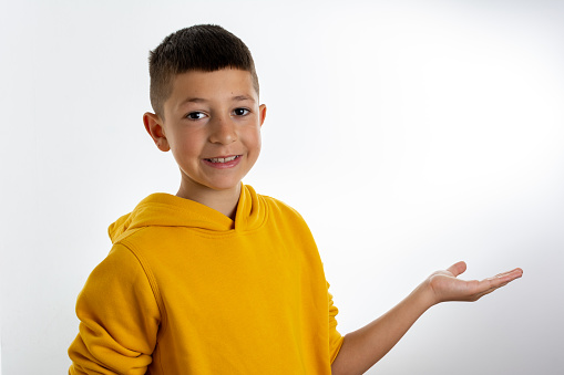 Wow, look. Emotional pre-teen boy pointing aside at empty space, bright white background. surprised boy showing copy space for promotional ad. indoor studio shot. Amazed kid pointing at copy