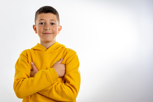 Happy young Caucasian boy in casual outfit with arms crossed isolated over white background. Confident Caucasian little boy smiling arms crossed looking at the camera isolated on a white background