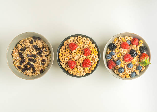 istock three bowls of cereal with berries on a white table, top view, copy space 1454223630