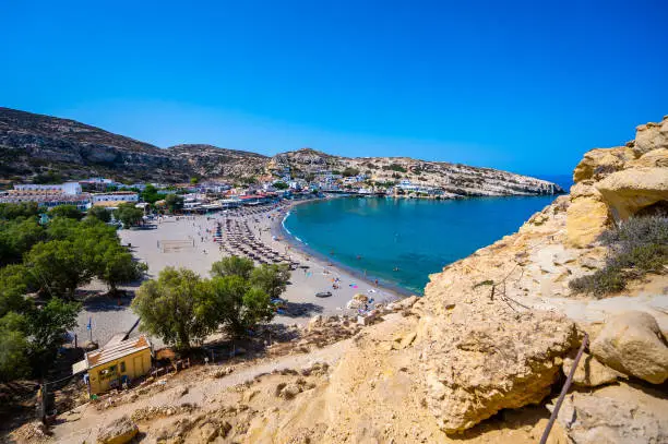 Famous Matala beach with caves, known for hippies in the 70's. View of the beach from rock caves, once a roman cemetery, in famous greek beach Matala, Crete, Greece.