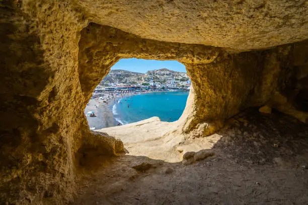 Famous Matala beach with caves, known for hippies in the 70's. View of the beach from rock caves, once a roman cemetery, in famous greek beach Matala, Crete, Greece.