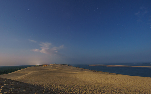 Night with stars in the sky on a huge natural sand formation Dune du Pilat illuminated by the moonlight, Arcachon, Nouvelle-Aquitaine, France