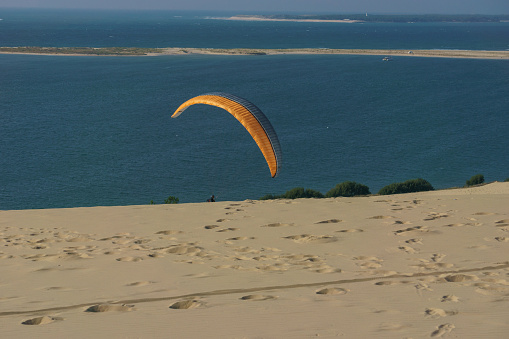 Single paraglider with parachute at the dune of Pilat on a sunny day, Arcachon, Nouvelle-Aquitaine, France