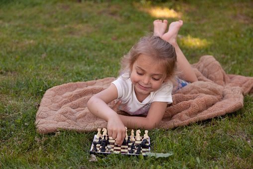 Happy child arranging chess pieces on the chessboard in the park