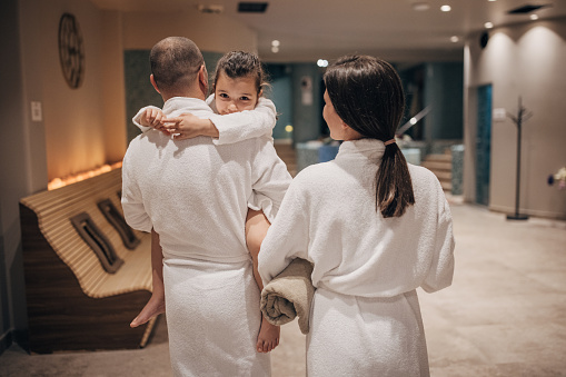 Group of people, husband and wife together in hotel spa with their little daughter.