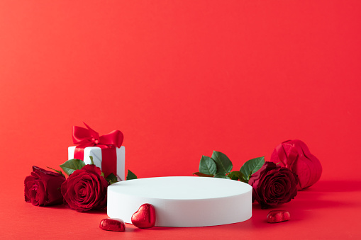 Abstract empty white podium, hearts and rose flowers on red background. Mock up stand for product presentation. 3D Render. St valentines day promotion concept.