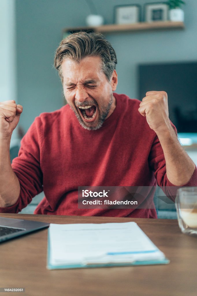 Exhausted businessman screaming Cropped shot of a handsome young businessman shouting angrily at his laptop while working. Overworked young man yelling at contract in front of him 45-49 Years Stock Photo