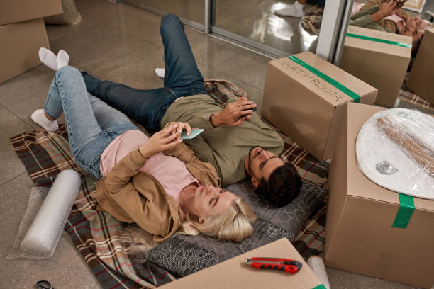istock Young couple using smartphones on blanket on floor 1454233336