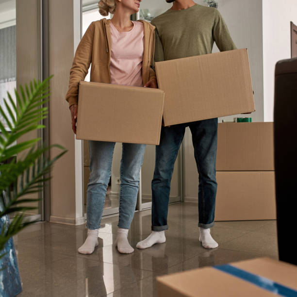 istock Obscure faces of couple carrying boxes in new flat 1454235270
