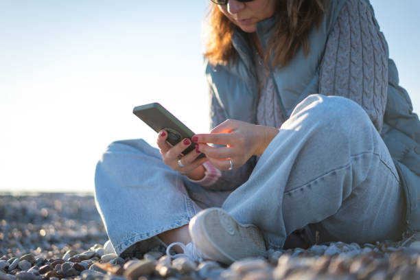 istock Mature beautiful caucasian woman using phone at the beach. 1454235584