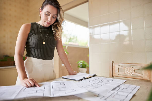 istock Woman architect reviewing blueprints standing in design office 1454236554