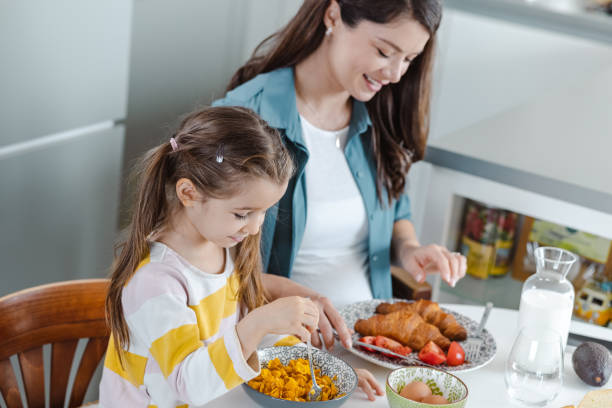 istock Mother and daughter eating in the kitchen 1454236833