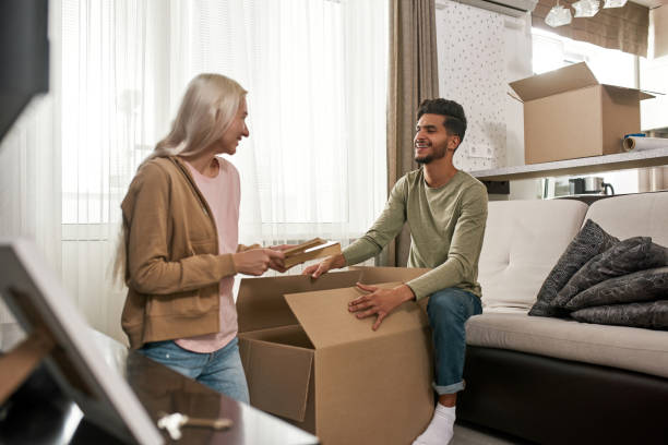 istock Girl packing books in box and looking at man 1454237638