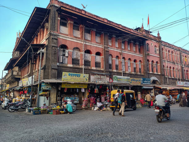 Kolhapur,India- November 6th 2022; Stock photo of Kolhapur Municipal Corporation building, small commercial shop at the ground floor, street vendor near the budding. people and vehicle moving on road stock photo