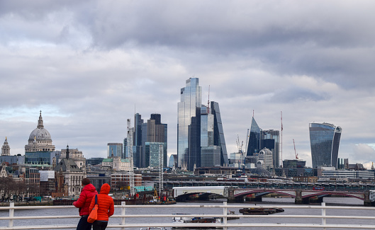 London, UK - January 2 2023: People walk along Waterloo Bridge past the City of London skyline