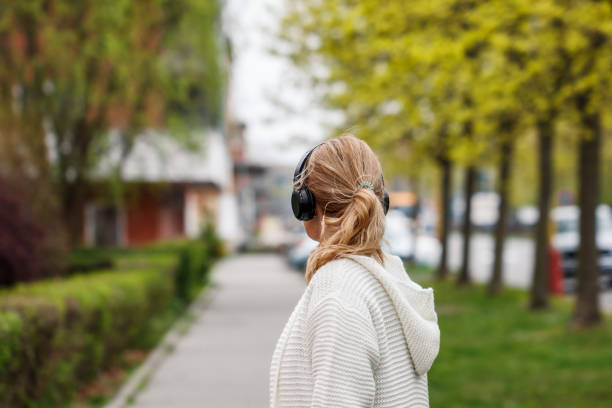 woman with headphones walking on city street - back alley audio imagens e fotografias de stock