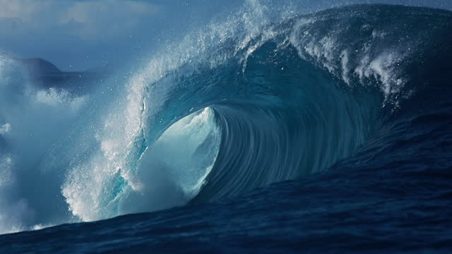 Large powerful blue ocean wave breaking in slow motion