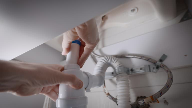 The plumber fixes a leak in the plumbing system, and collects the sink siphon.