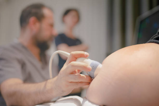 Gynecologist using ultrasound scanner while examining female patient