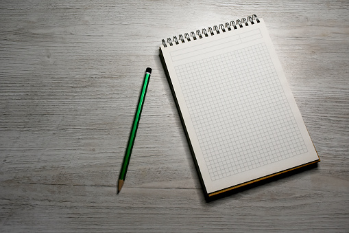 Top view open blank notebook and pencil on a light wooden table, copy space