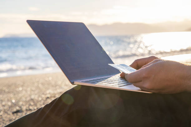 istock Close up of young man using laptop, at beach 1454245235