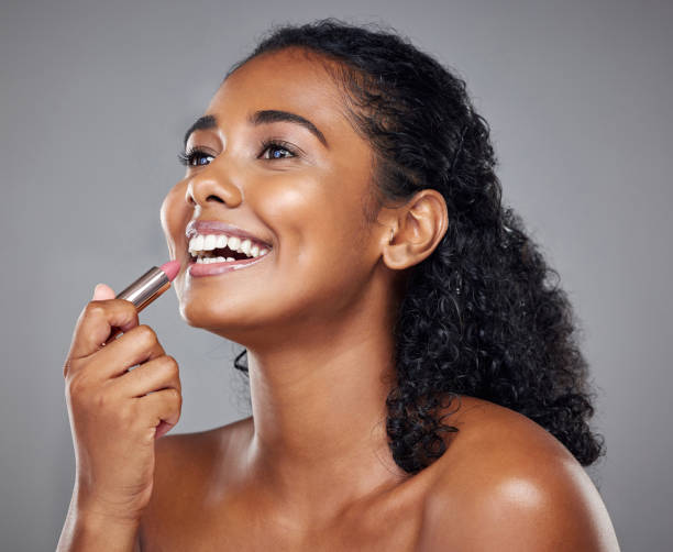 istock Lipstick, makeup and black woman with smile, thinking and idea against a grey studio background. Happy, young and African model with cosmetics, facial care and dermatology for beauty with a glow 1454247527