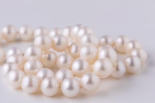 a very beautiful delicate pearl necklace close-up on a light background , a gift to a beloved woman