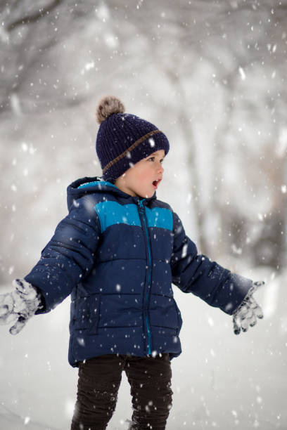 istock Adorable, cute boy playing with snow cheerfully. Wintertime, kids activity 1454251100