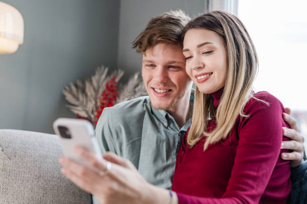 istock Young couple using smart phone in the living room 1454251253