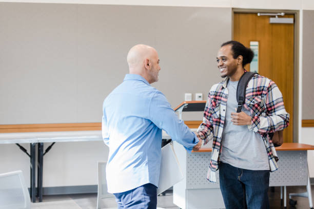 Mature professor greets young male college student