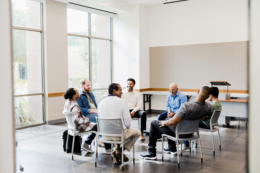 The multiracial group of men enjoy laughing together during their monthly support group meeting.