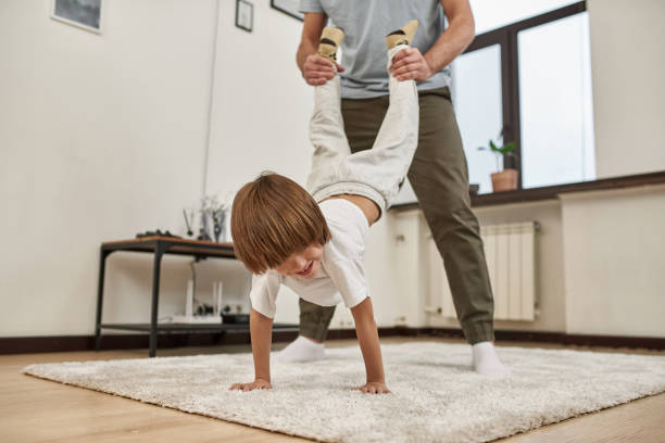 istock Father holding legs of son standing on hands 1454251587