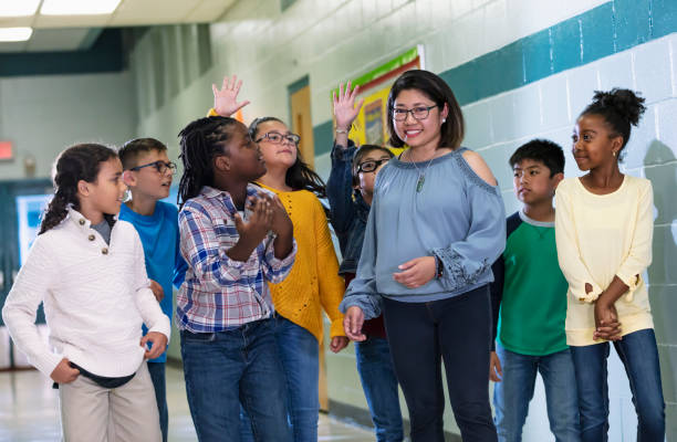 istock Asian teacher with elementary students in school hallway 1454256590