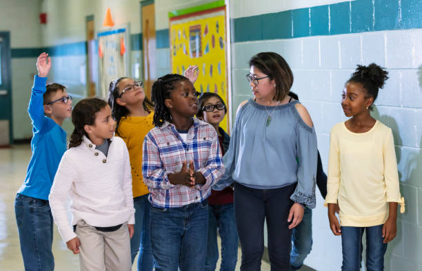 istock Asian teacher with elementary students in school hallway 1454256592