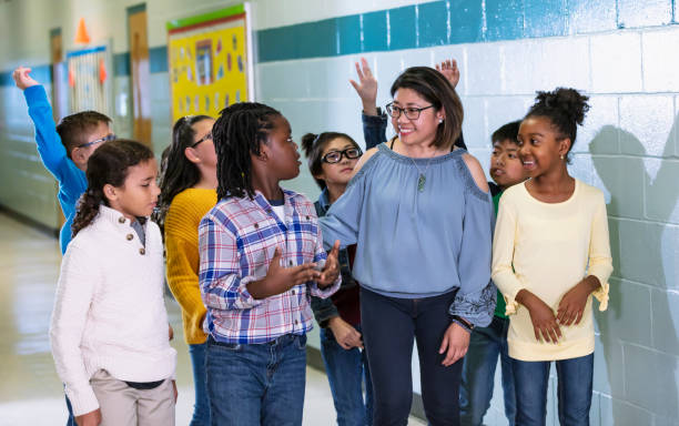 istock Asian teacher with elementary students in school hallway 1454256639