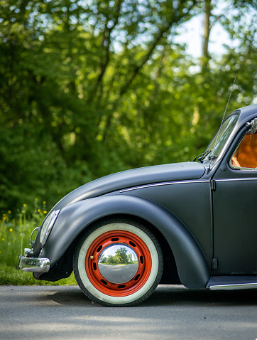 ZOETERMEER, Netherlands – May 27, 2021: Black retro car VW Beetle with orange windows in a forest.