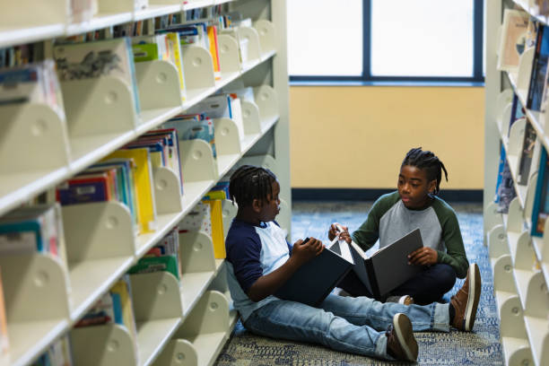 istock Two African-American boys reading on library floor 1454258978