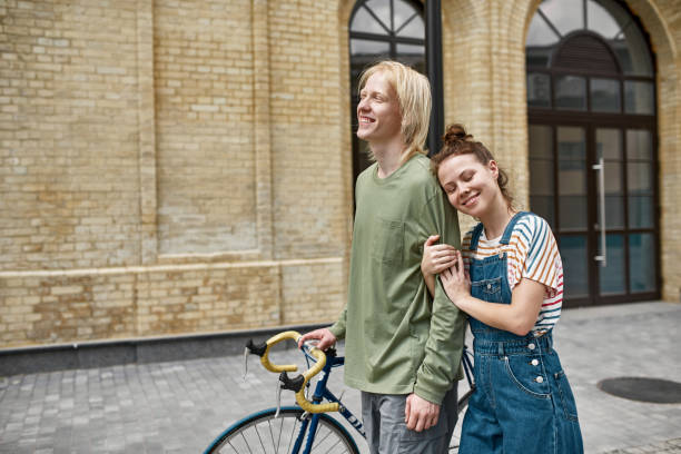 istock Smiling guy and pleased girl walking with bicycle 1454260434