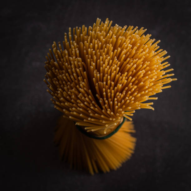 Raw spaghetti tied with a rope, black background. Seen from above.