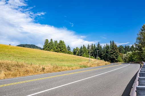 Scenic summer landscape with a winding mountain highway road with security fence and trees in Columbia Gorge area allows tourists and travelers to visit all corners of the famous national reserve