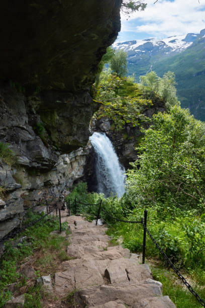 The impressive Storseterfossen (Storsæterfossen) with a path leading behind it throwing water down towards Geiranger stock photo