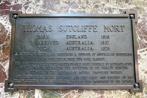 Plaque attached to the base of a bronze statute which was erected in memory of Thomas Sutcliffe Mort in 1883 at Macquarie Place, Sydney.  He was a significant figure in the development of wool industry and exporting agricultural products to the United Kingdom.  This image was taken on a sunny afternoon in summer.
