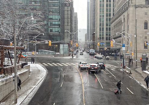 Toronto, Canada - December 11, 2022: Pedestrians and motorists share the intersection on York Street at Front Street West. Looking north on York Street to the hotels and office buildings lining this section of the Financial District. Winter conditions on a weekend morning.