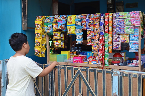 Indonesia - Jan 1, 2023 : Asian boy buys snack at the stall