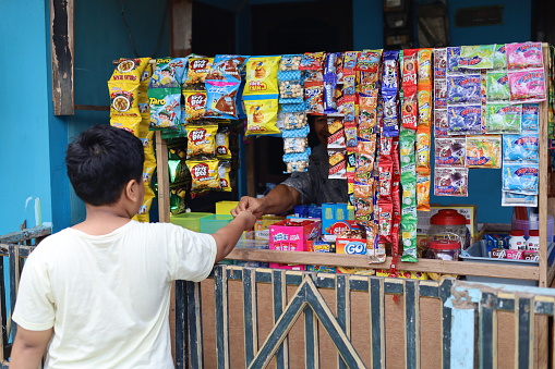 Indonesia - Jan 1, 2023 : Asian boy buys snack at the stall