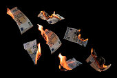 Burning money, twenty and fifty euro banknotes with flames flying isolated against a black background, concept for inflation, finance, investment risk and currency, copy space, selected focus